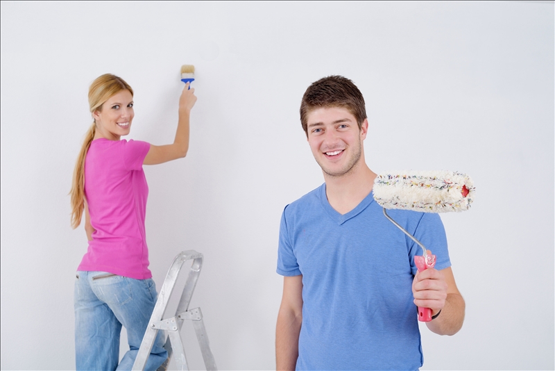 happy young couple paint in green and blue color white wall of their new home